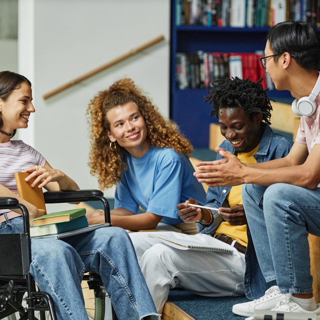 Group of people chatting while sitting together on a bench.