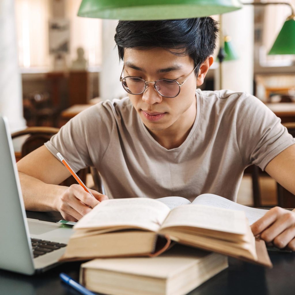 A young man concentrating on his studies with a laptop